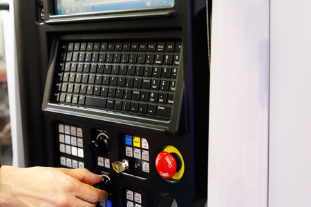 Operator working with CNC lathe machine using control panel. Selective focus.