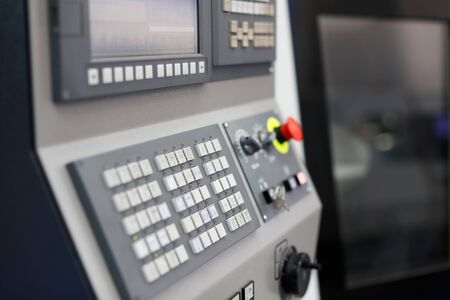Modern lathe machine with CNC control panel in the foreground. Selective focus.