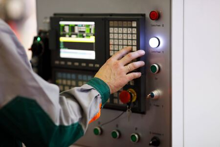 Operator programs the CNC manufacturing machine. Selective focus.