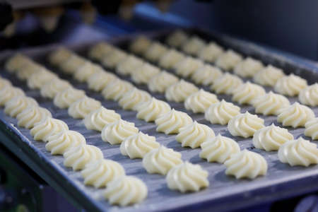 Butter swirl whipped shortbread cookies on the tray at the production line. Selective focus.