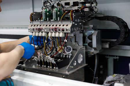 Male technician performs maintenance work on large format floor standing fabric printer.