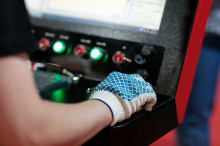 Worker controls modern computerized machine in metalworking plant. Selective focus.