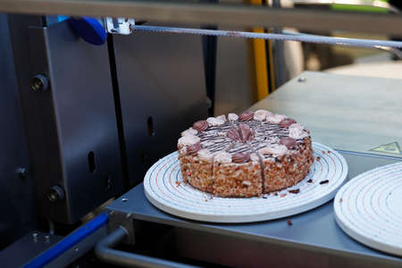 Automatic round cake cutting machine. Industrial cake slicer. Selective focus.
