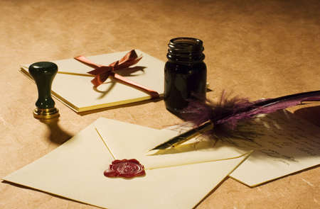 Letters with a quill, an inkwell & a stamp on a rustic paper. 