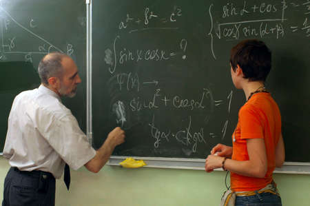 The teacher and the schoolgirl near blackboard. Lesson of mathematics