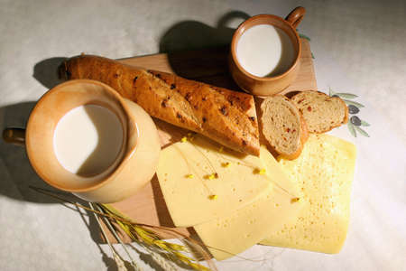 Still-life with cheese, bread and milk in a ceramic jug and mug.の写真素材