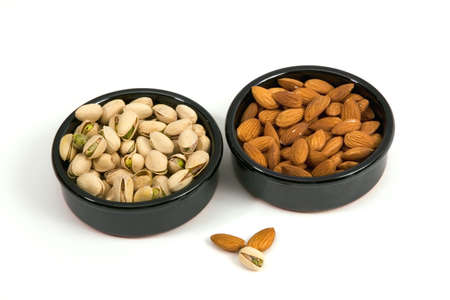 Pistachios and almonds in a ceramic bowl isolated on a white background.の写真素材