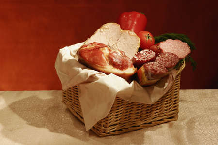 Still-life with various sausages and meats with a vegetables in a basket.の写真素材