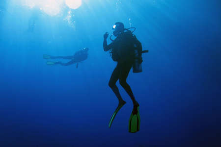 A scuba diver decompressing after dive. Surrounding waters are serene and penetrated by sun beams.の写真素材