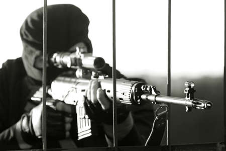 Sniper in a camouflage shoots from a rifle.の写真素材