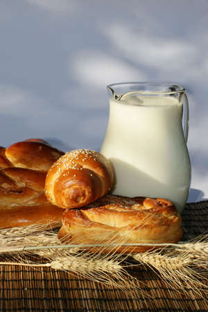 Baking bread, wheat ears and jug with milk on a bamboo mat. の写真素材