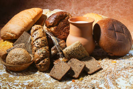 Still-life with  different bread products and jug of milk on brown classical background