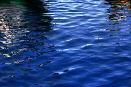 Rhythmical water pattern with multi-colored waves and solar patches of light の写真素材