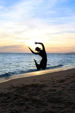 Silhouette jumping woman  on a beach. Sunsetの写真素材