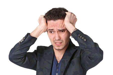 Portrait of  upset young man grabbing his head in desperation over white background