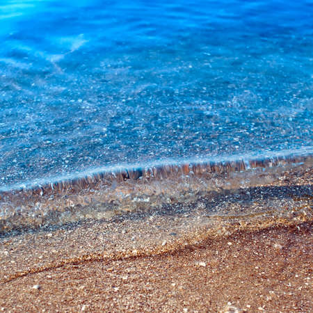 Waves on shore of gilded sand beachの写真素材