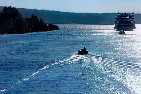 Silhouette of motor boat and cruise  ship on the Volga river at sunset.  Beautiful river landscape.