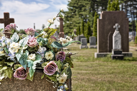 Flowers on a headstones in a cemetery, bokeh effect in background.の写真素材