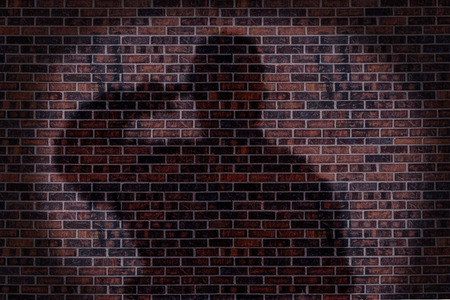 Military soldier saluting, shadow on a brick wall.の写真素材