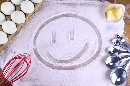 Happy face made with cooking flour on a wooden table. Top view.の写真素材