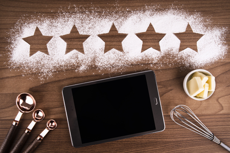 Five star product quality rating on cooking background. Digital tablet ready to create mock up. Top view.の写真素材