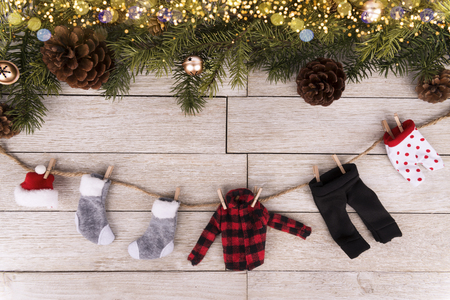 Winter clothes hanging up. A tree branches and a wooden table in background. Directly above. Christmas holiday concept.の写真素材