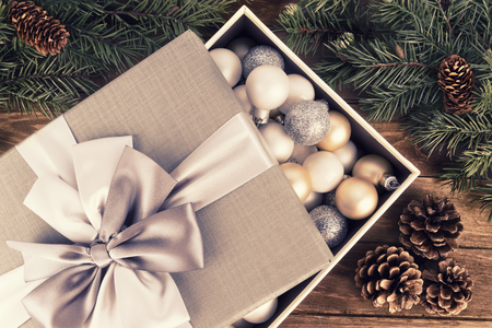 Christmas bauble decoration in a gift box with ribbon and bow. Flat lay. Wooden background.の写真素材