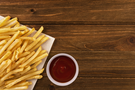 French fries with ketchup on a wooden background, directly above. Close up.の写真素材