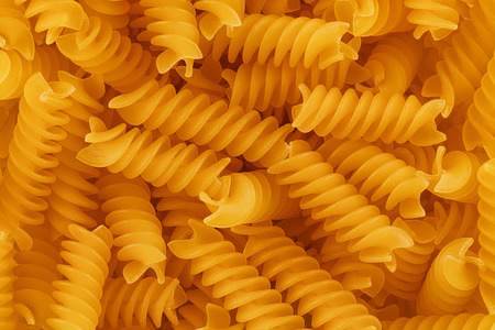 Top view on background texture of uncooked fusilli pasta. Copy space for your text.
