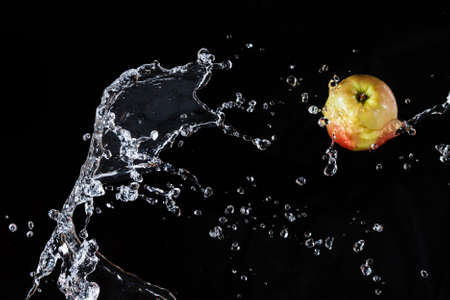 Apple flying in space, along with water on a black backgroundの写真素材