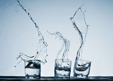 Big splash in glasses of alcoholic drink on a blue backgroundの写真素材