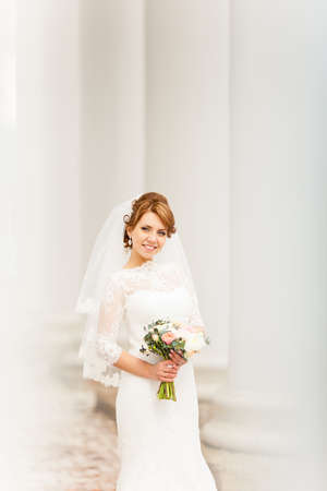 Bride portrait with a bouquet on a background of columnsの写真素材