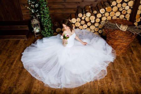 Young sexy bride in the studio is sitting on the wooden floorの写真素材