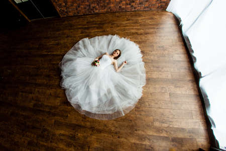 Young sexy bride in the studio is lying on the wooden floorの写真素材