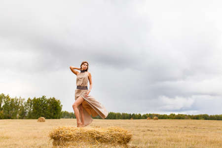 Young beautiful woman standing on the haystack at susetの写真素材
