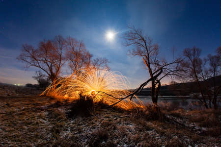 Night winter landscape and sparks from the burning steel woolの写真素材