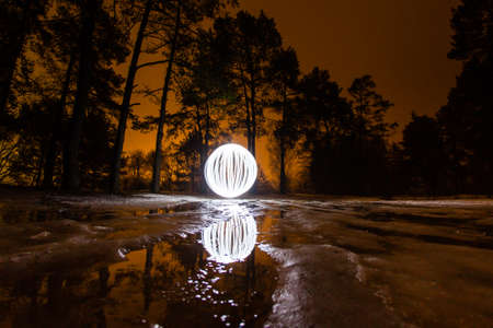 Glowing ball on winter road in a full moonの写真素材