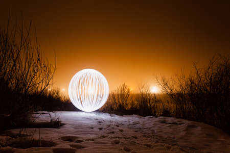 Futuristic glowing sphere on a background of a beautiful winter landscape in full moonの写真素材