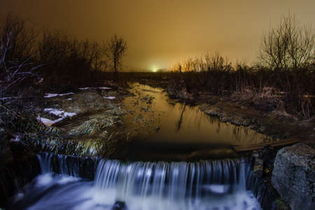 Night winter landscape with a creek and waterfallの写真素材