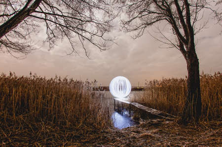 Futuristic glowing sphere on a background of a beautiful autumn landscape in full moonの写真素材