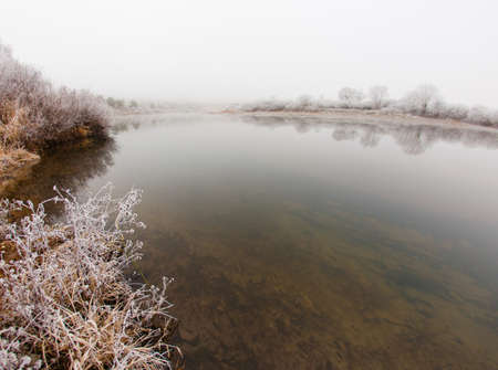Autumn frosty morning by the river with fogの写真素材