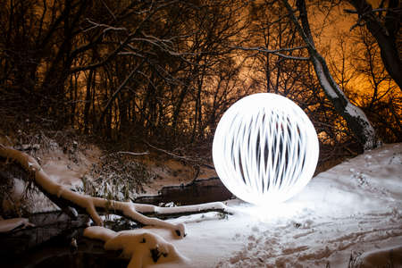 Futuristic glowing spiral on a background of a beautiful winter landscape in full moonの写真素材