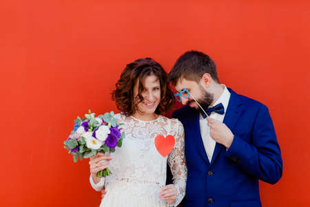 Bride and groom standing next to a red wallの写真素材