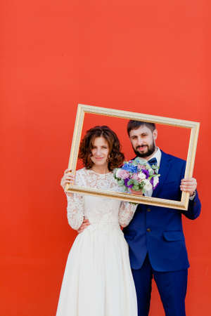 Bride and groom standing with a frame from the pictureの写真素材