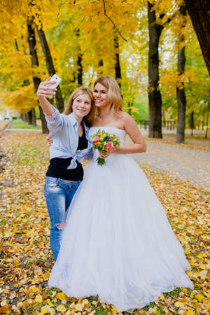 Wedding photographer shooting a selfie with the bride in the autumn parkの写真素材