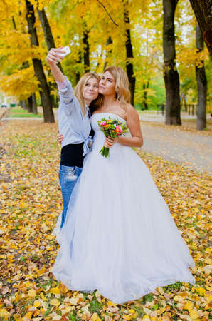 Wedding photographer shooting a selfie with the bride in the autumn parkの写真素材
