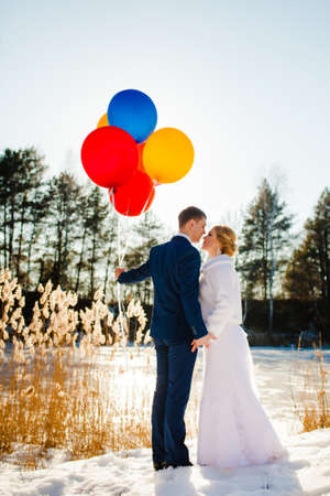 Bride and groom are standing near the frozen lake at sunsetの写真素材