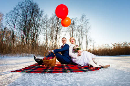 Bride and groom are sitting on the plaid with balloonsの写真素材