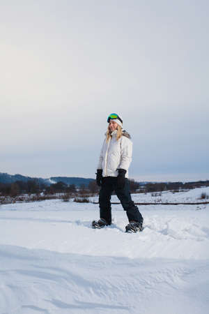 Young woman and her white snowboard on snow-covered mountainsideの写真素材