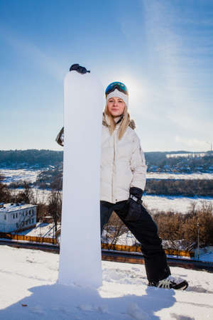 Young woman and her white snowboard on snow-covered mountainsideの写真素材
